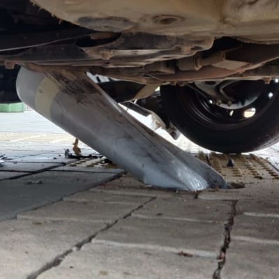 צינור מתכת מעוקם מתחת לרכב על כביש