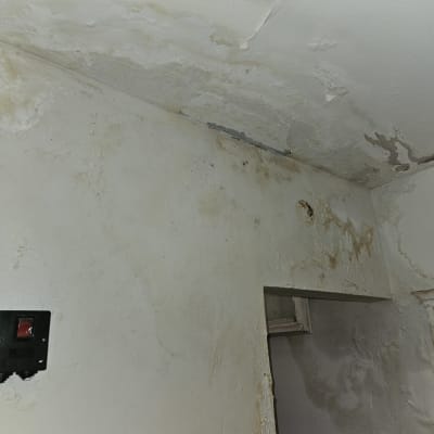 קיר ותקרה עם סימני רטיבות והתקלפות צבע