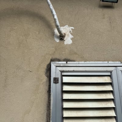 צינור מיזוג אוויר מחובר לקיר ליד חלון תריסים.