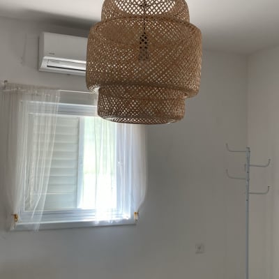 מנורת תקרה קלועה בחדר עם חלון ווילון לבן