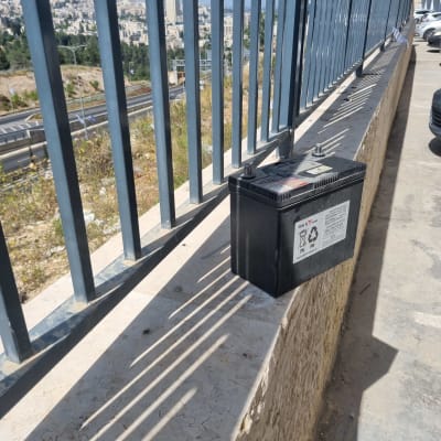 מצבר רכב מונח על קיר ליד כביש