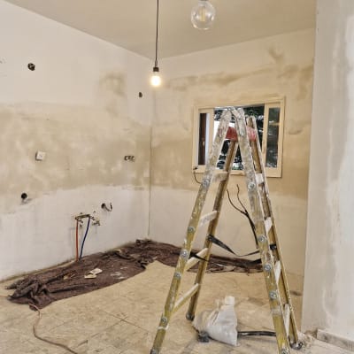 חדר בשיפוץ עם סולם ונורות תלויות