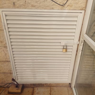 תריס מתכת עם מנעול תלוי על קיר אבן