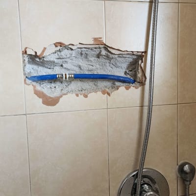 צינור מים חשוף בקיר מקלחת עם ברז וכיור