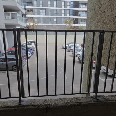 מעקה מתכת מול חניון עם מכוניות
