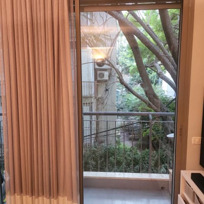 חלון זכוכית עם וילון ונוף חיצוני של עצים