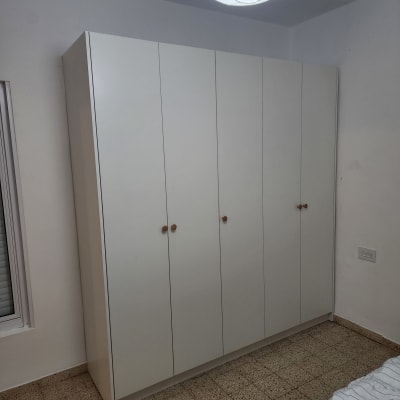 ארון בגדים לבן עם ידיות עץ בחדר שינה