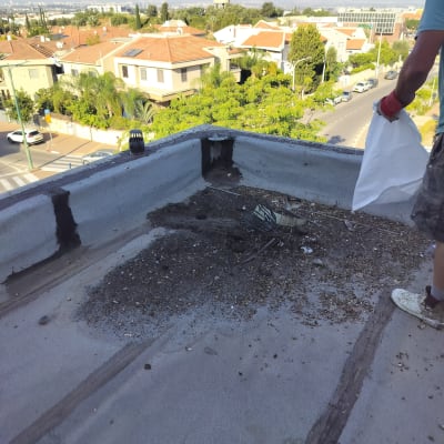 אדם עם שקית על גג, איטום גג עם זפת.