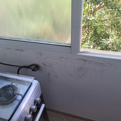 קיר עם סימני לכלוך ליד חלון ותנור גז