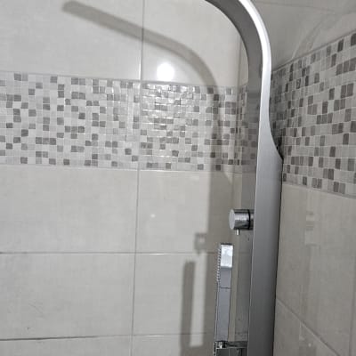 ראש מקלחת מודרני על קיר אריחים בחדר אמבטיה