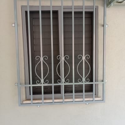 סורג מתכת אפור על חלון עם תריסים סגורים