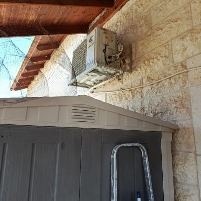 רשת יונים מותקנת ליד מזגן על קיר חיצוני