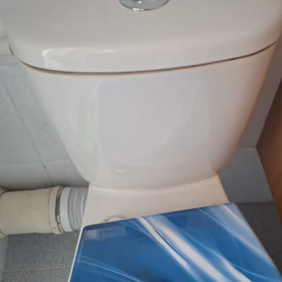 אסלה עם צינור חיבור לבן על קיר אריחים