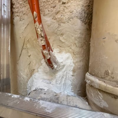 צינור כתום אטום בחומר לבן על קיר