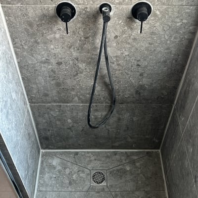 תא מקלחת עם אריחים אפורים וברזים