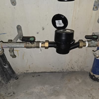 מד מים וצנרת מותקנים על קיר בטון