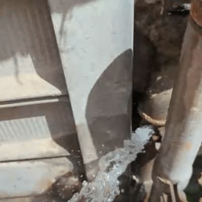 מים זורמים מצינור פגום ליד קיר חיצוני