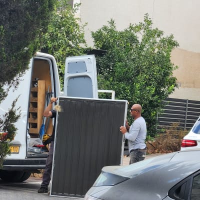 שני אנשים עובדים עם פאנל סולארי ליד רכב מסחרי