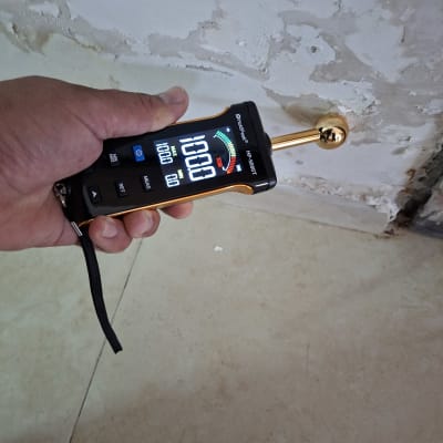 מד לחות נוגע בקיר עם סימני רטיבות