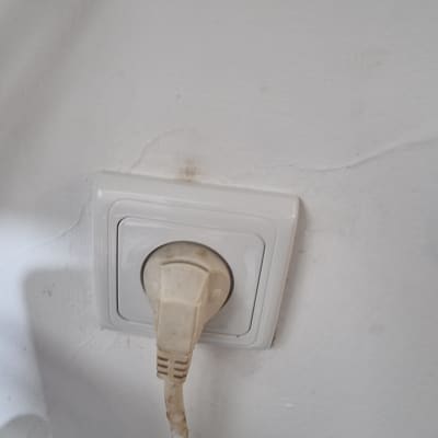 שקע חשמל עם תקע מחובר לקיר לבן