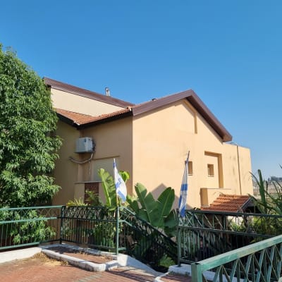 גג רעפים חום על מבנה צהוב עם דגלים