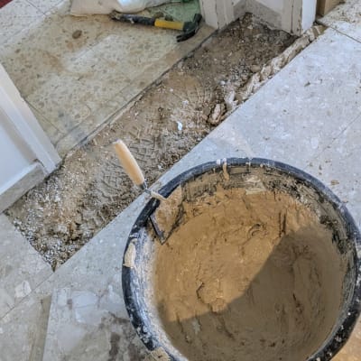 דלי עם טיט, מרצפות, פטיש ושקיות בנייה