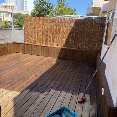 מרפסת עץ עם גדר במבוק וכלי ניקוי על הרצפה