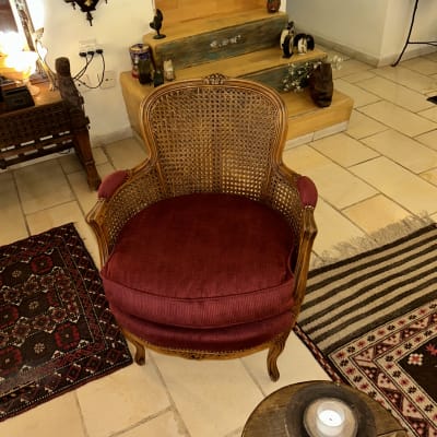 כורסה עתיקה עם גב קש ומושב מרופד בבד בורדו