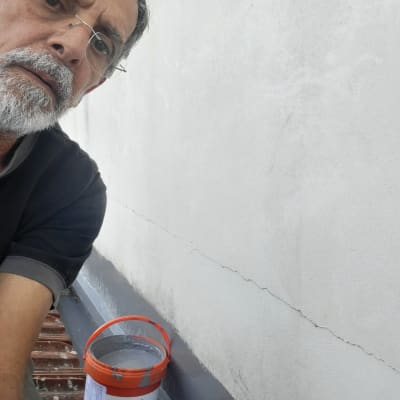 דלי צבע ומברשת ליד קיר עם סדק