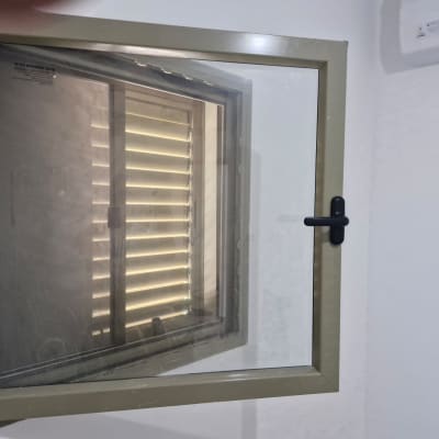 חלון עם תריסים פנימיים נראים דרך הזכוכית