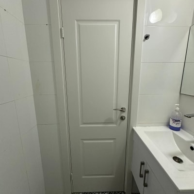 דלת לבנה עם ידית מתכת בחדר אמבטיה