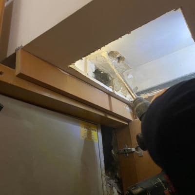 אדם משתמש במקדחה לתיקון נזילה בתקרה