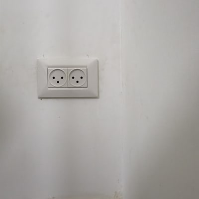 שקע חשמל כפול על קיר עם צינור ירוק