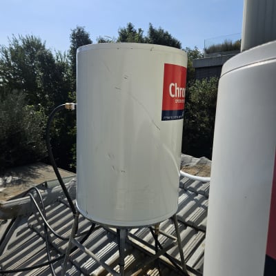 דוד שמש לבן על גג עם צינורות וחיבורים