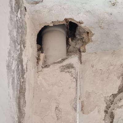 קיר עם חור ותקרה מתקלפת סביב צינור