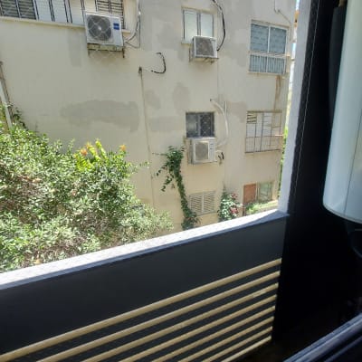 רשת יונים על חלון עם מזגנים על קיר חיצוני