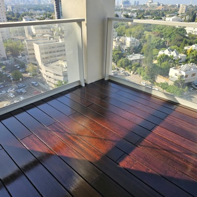 רצפת עץ כהה במרפסת עם מעקה זכוכית