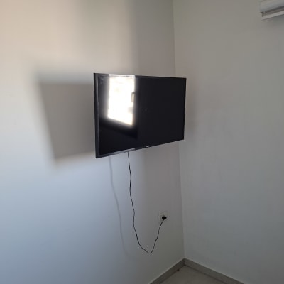 טלוויזיה תלויה על קיר עם כבל חשמל