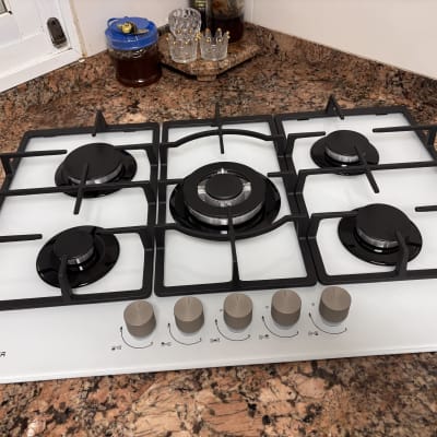 כיריים גז לבנות מזכוכית המותקנות על משטח שיש במטבח