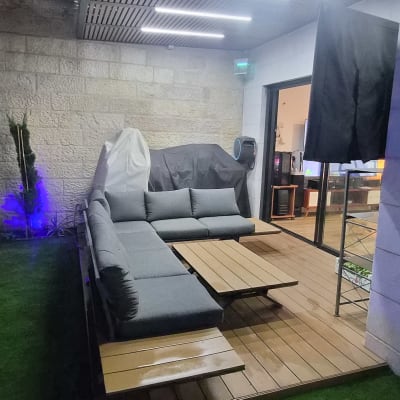 פינת ישיבה בגינה עם תאורה צבעונית וצמחים קטנים