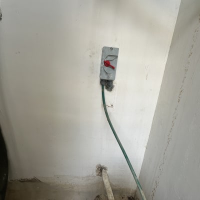 מתג חשמלי עם כבל ירוק על קיר לבן