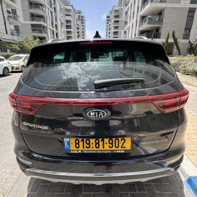 רכב שחור חונה ברחוב בין בניינים גבוהים