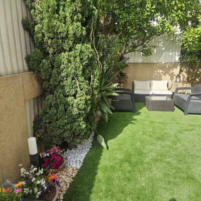 עציצים עם פרחים צבעוניים ודשא סינתטי בגינה