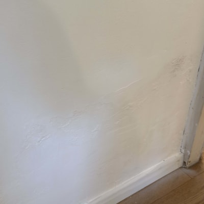 קיר צבוע עם סימני תיקון ליד הרצפה