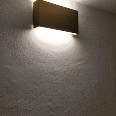 מנורת קיר מוארת על קיר לבן