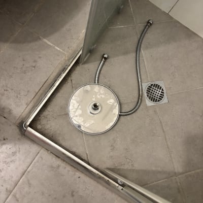 ראש מקלחת מנותק על רצפת מקלחת