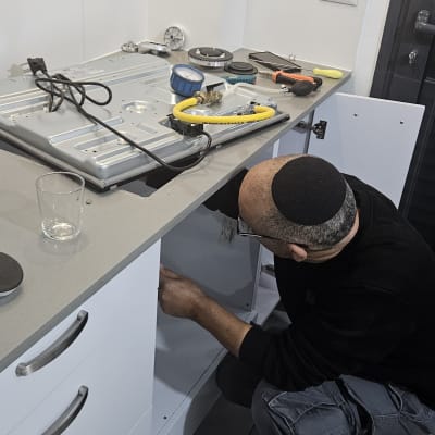 אדם מתקין כיריים במטבח עם כלים על השיש