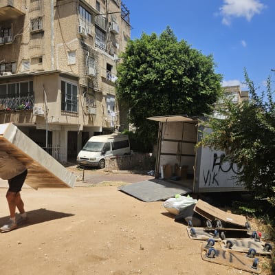 משאית פתוחה עם קרטונים וציוד הובלה בחצר בניין