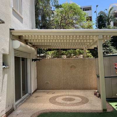 פרגולה בחצר עם צמחייה מסביב