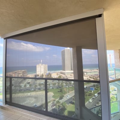 מרפסת עם סוכך שקוף נגלל על מסגרת מתכת